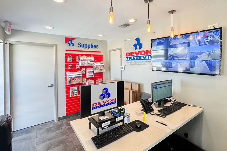 Self storage office interior with customer service desk, security monitors, and packing supplies